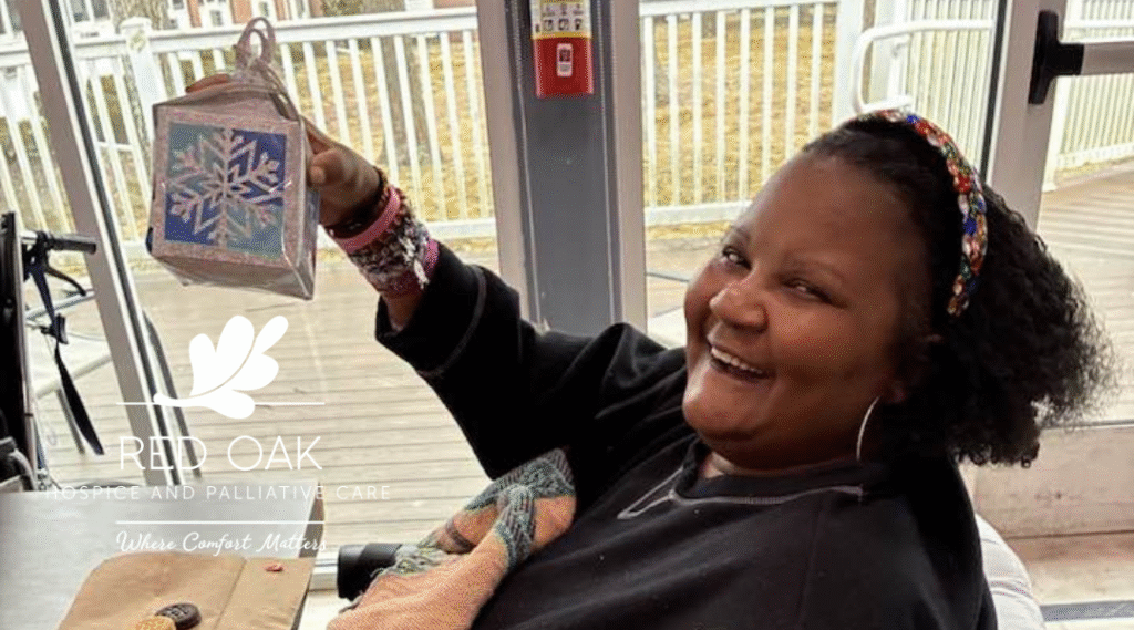 A smiling nursing home resident holding up a completed paper snowflake craft.
