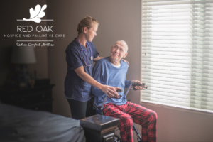 Caregiver supporting a senior man using a walker in a palliative care setting.
